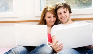 Smiling couple looking at dual laptops