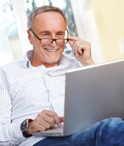 Senior man with glasses using laptop