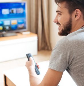 Profile of man with beard using a TV remote
