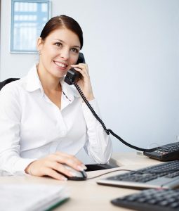 Woman in office, using business phone and computer