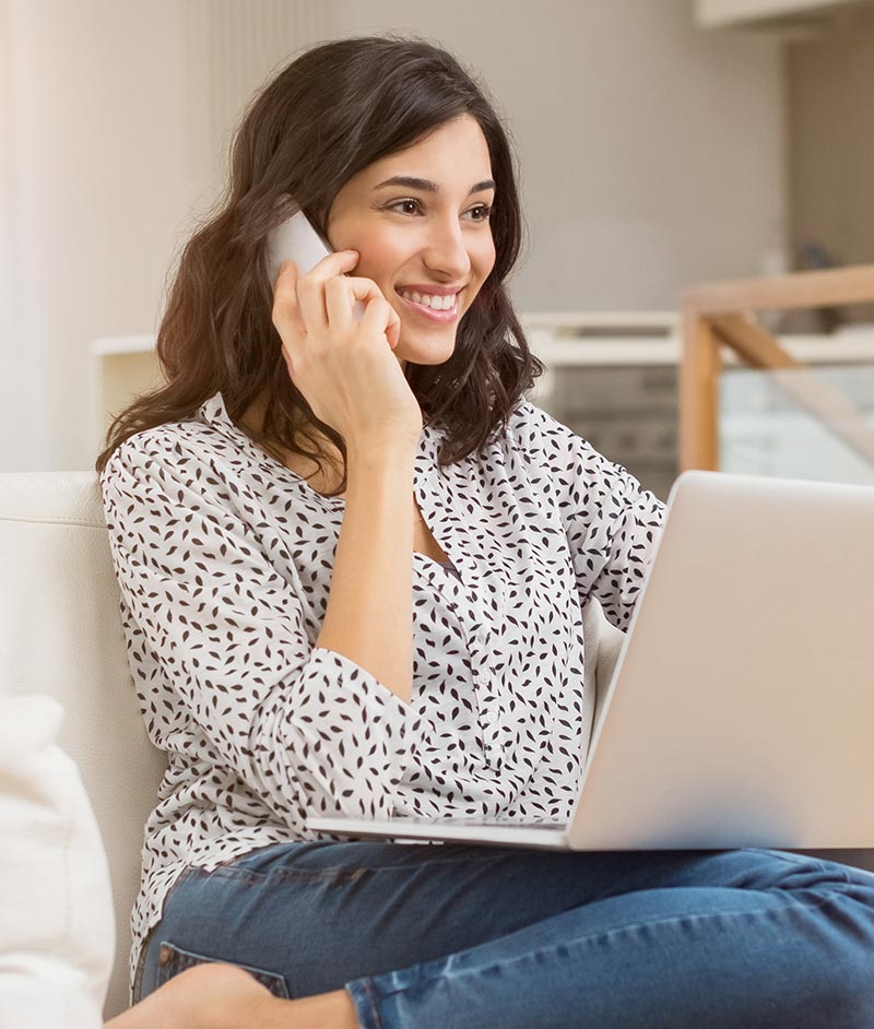 Attractive woman using cordless home phone and laptop